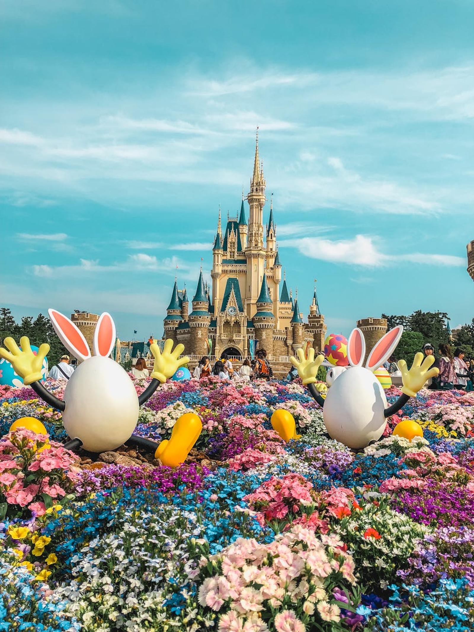Vibrant flowers and playful decorations adorn the iconic Tokyo Disneyland Castle in a festive springtime setting