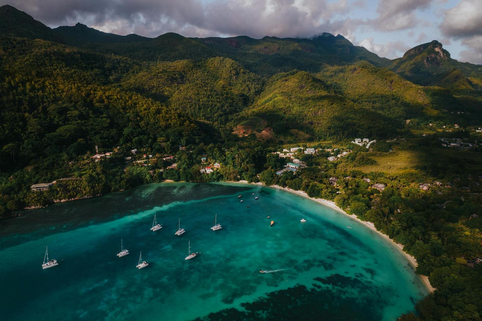 Aerial view of yachts anchored in a turquoise bay ringed by forested hills