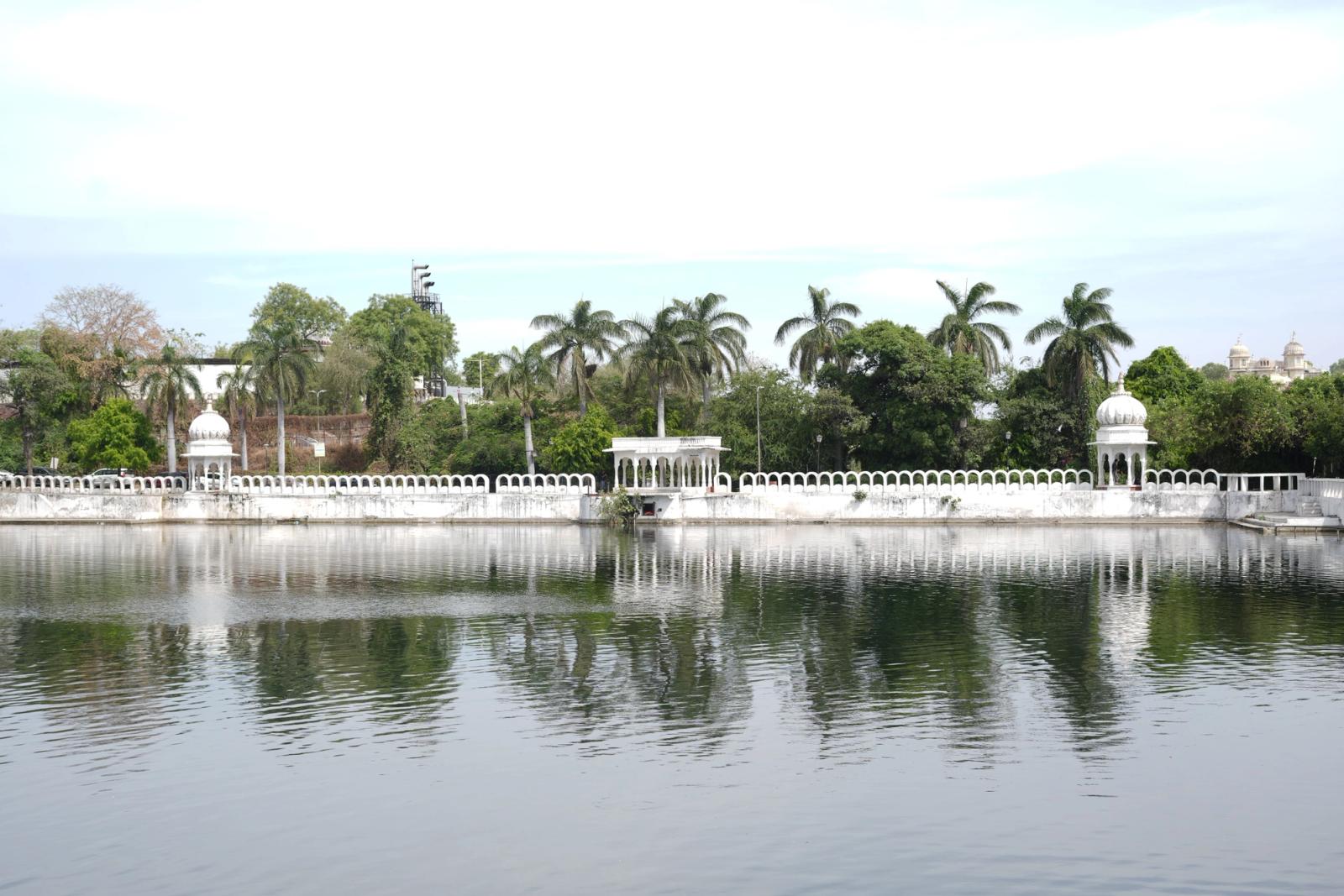 Tranquil lakeside view in Udaipur, showcasing historic architecture and lush greenery