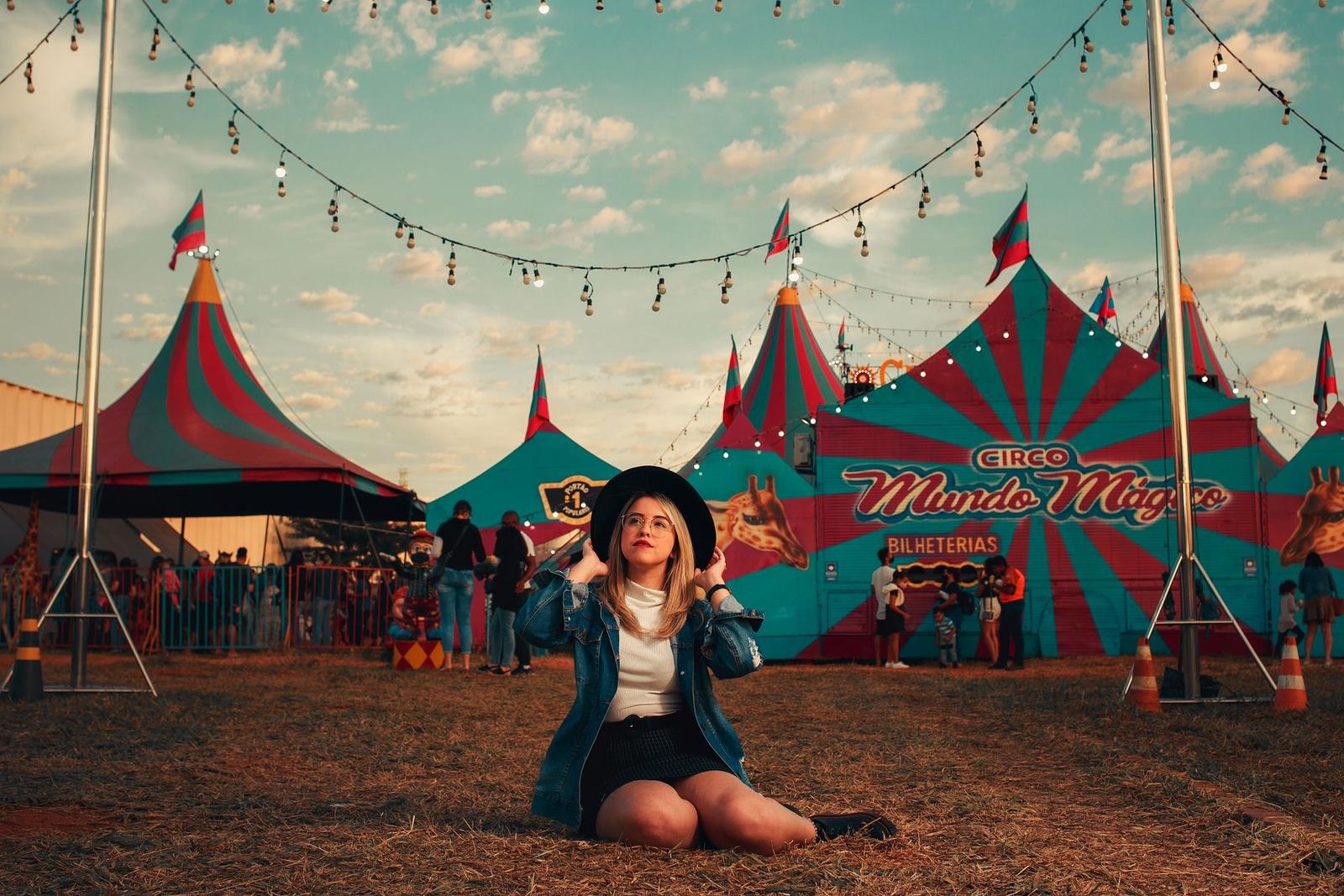 Woman seated on the ground before striped circus tents