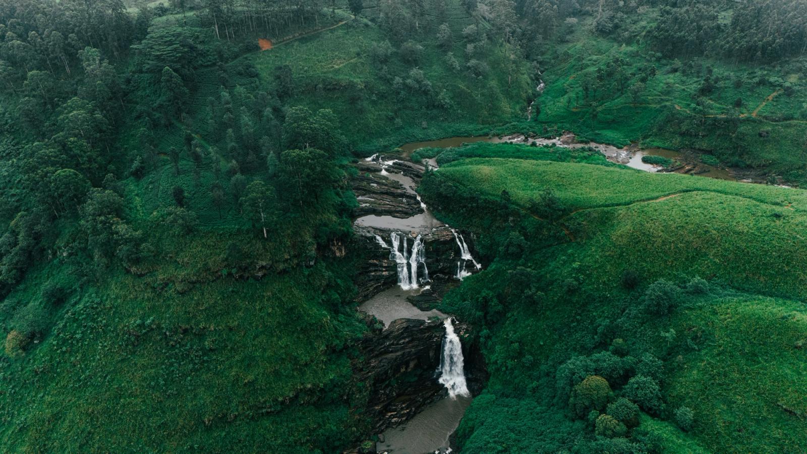 Explore the lush greenery and cascading waterfall in Sri Lanka from an aerial perspective