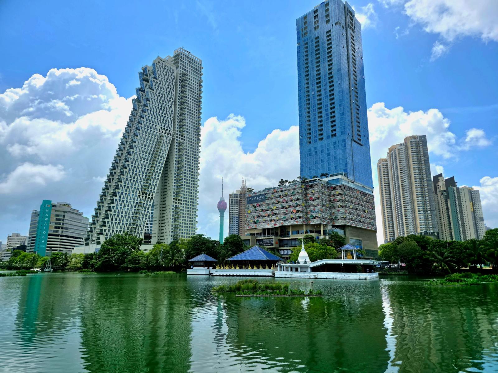A view of Colombo's skyline with high-rise towers reflecting in a serene lake