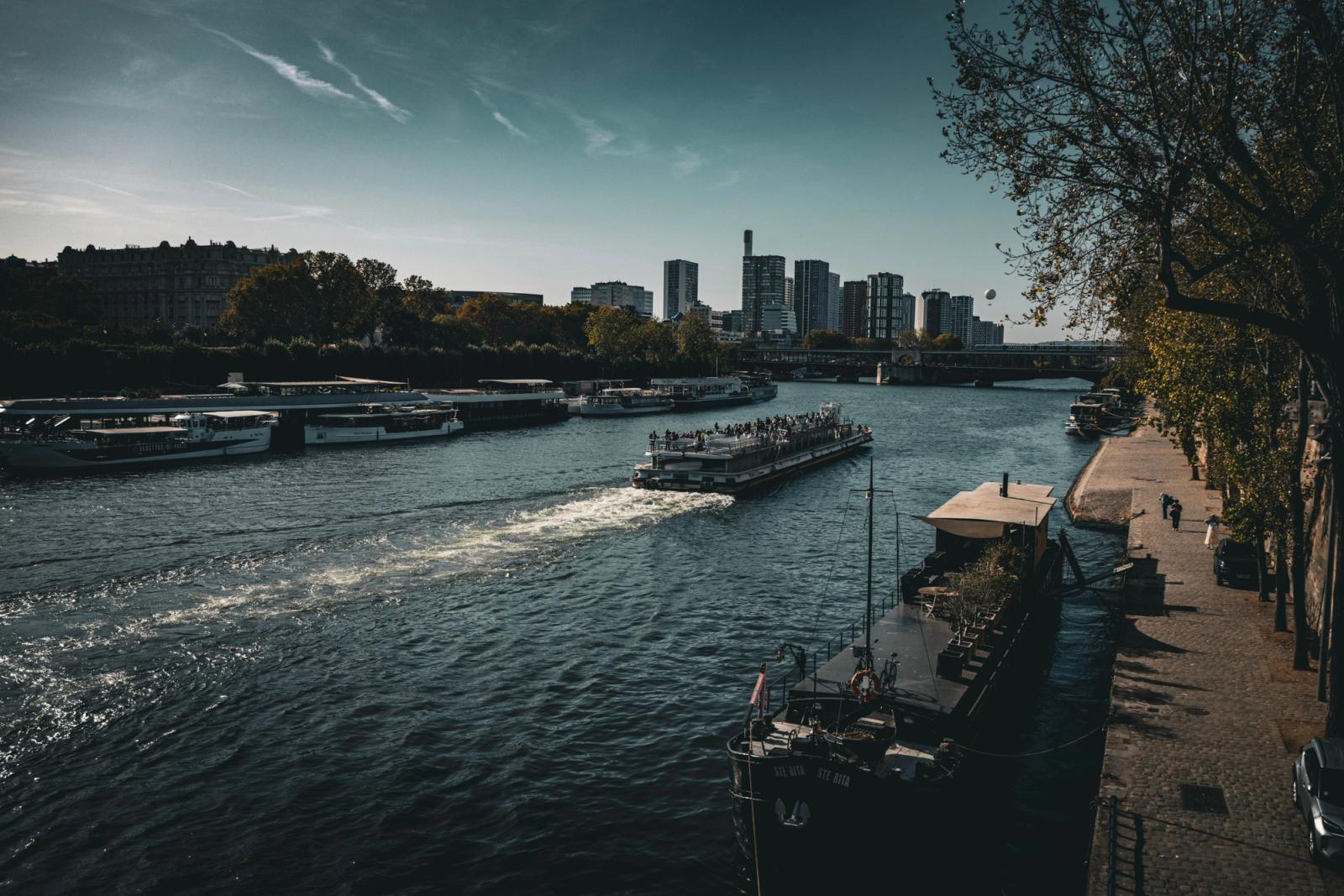 A busy river scene with boats and a modern city skyline on a sunny day