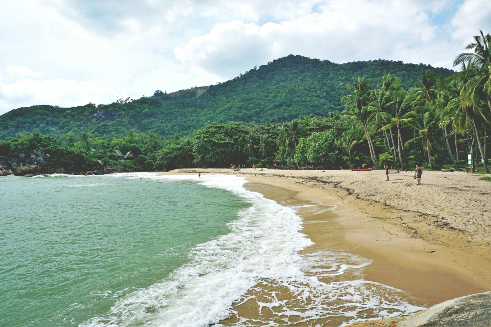 Explore the tranquil beach at Ban Tai, Thailand, with lush greenery and golden sands
