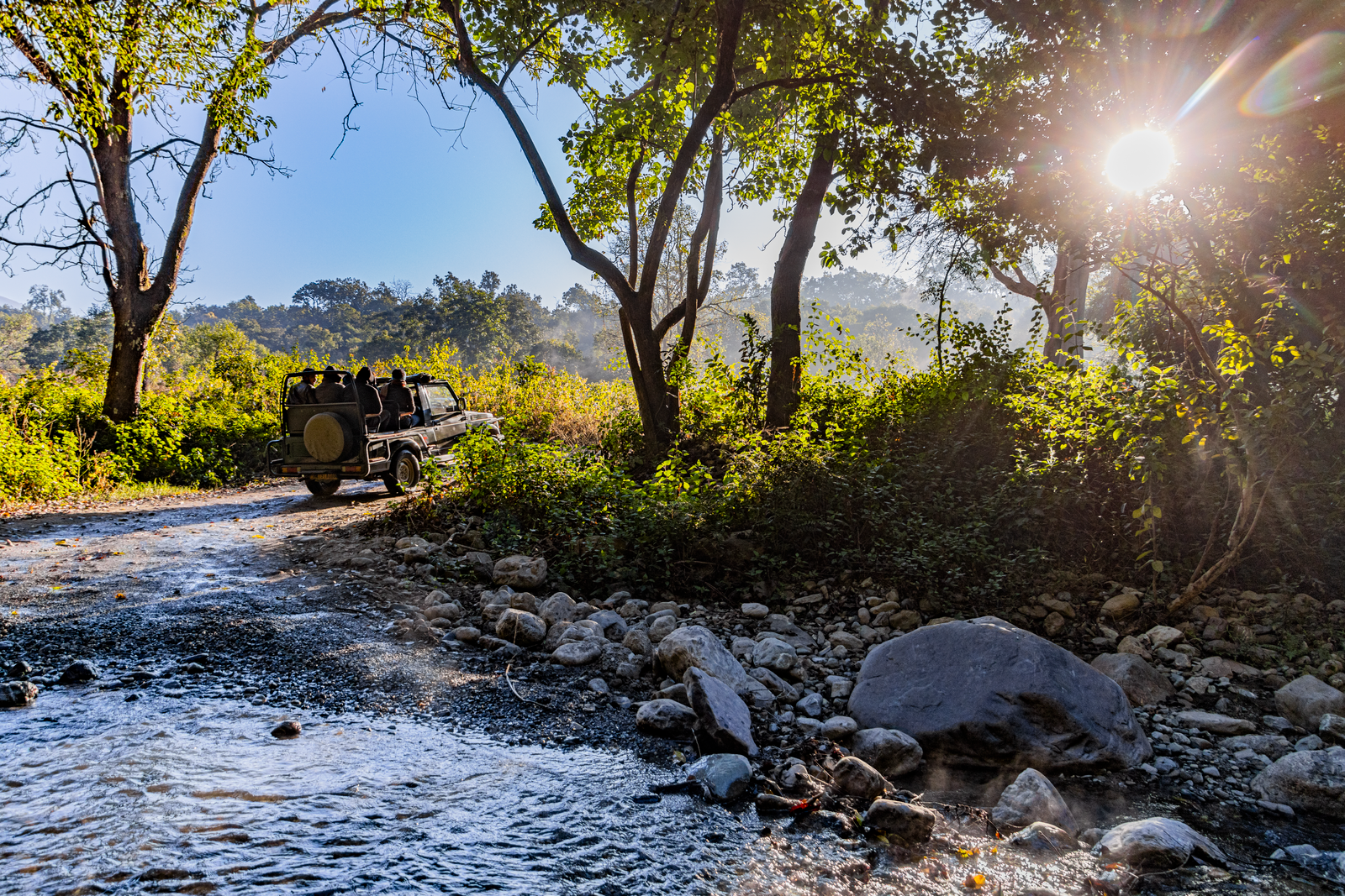 A safari jeep at a stream crossing in the Corbett forest at first light