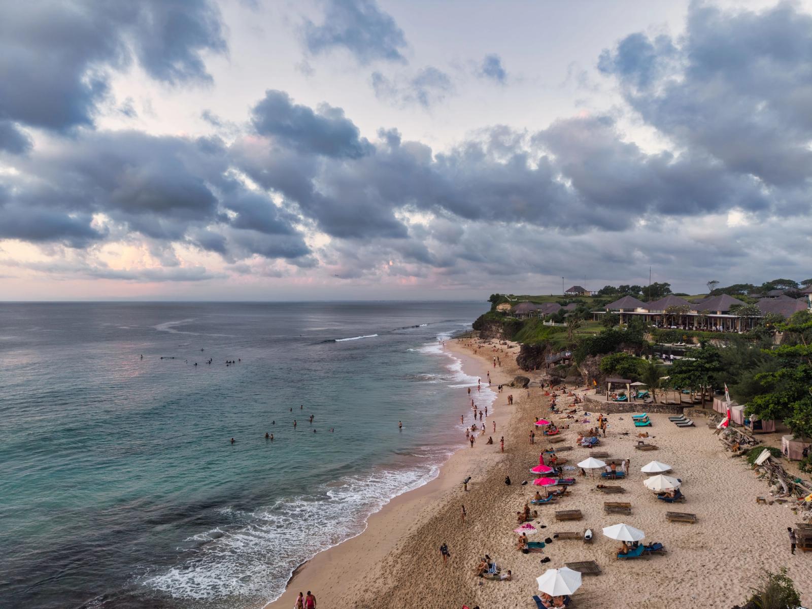 Stunning aerial view of a beach in Bali, Indonesia with visitors at sunset