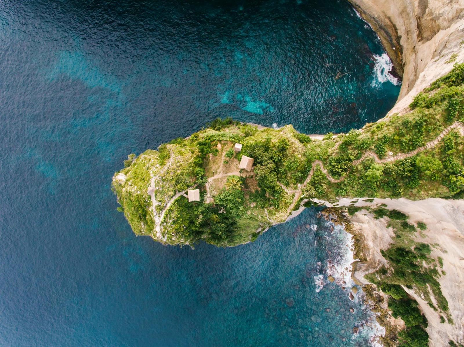 Aerial view of a narrow green headland trailing into turquoise sea