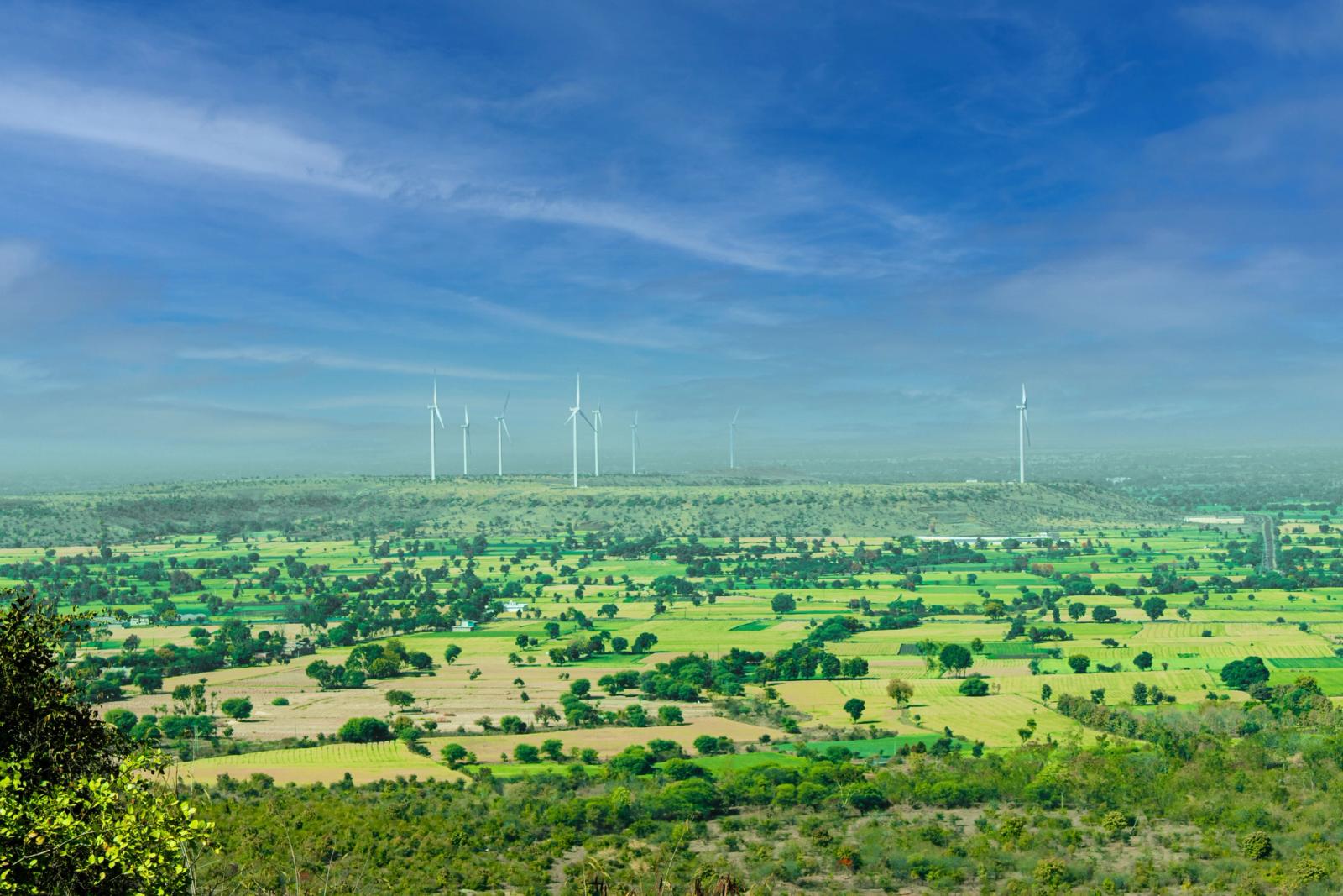 Wind turbines on a ridge above patchwork green farmland