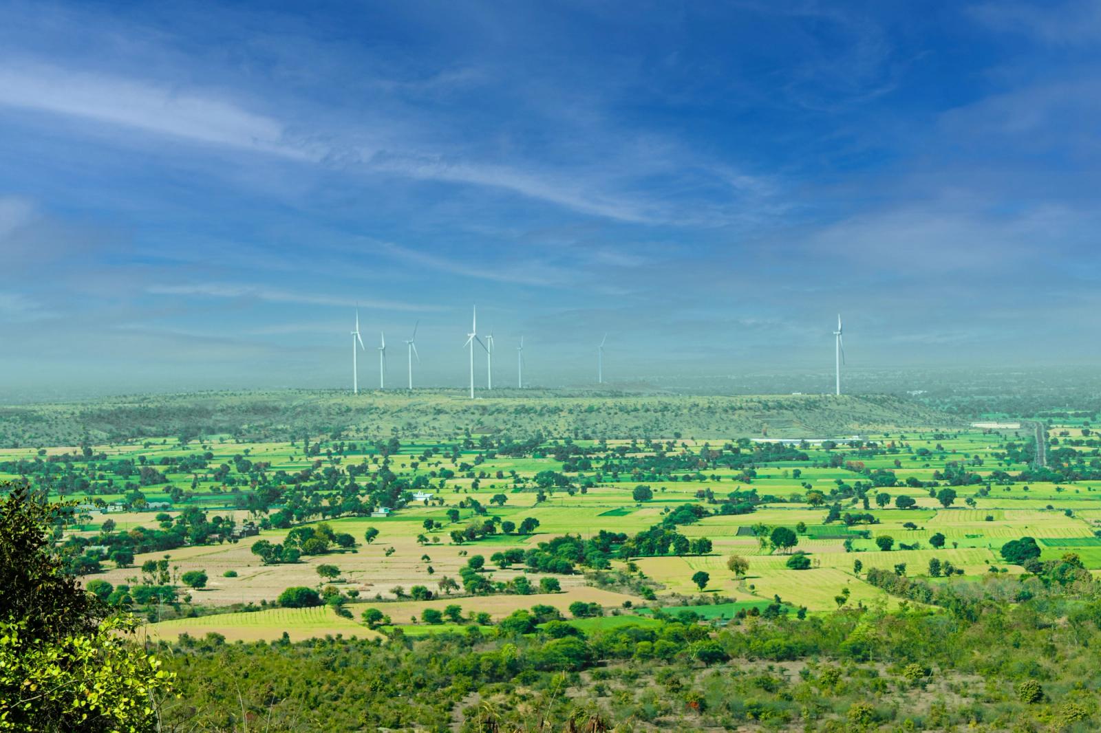Wind turbines on a ridge above patchwork green farmland
