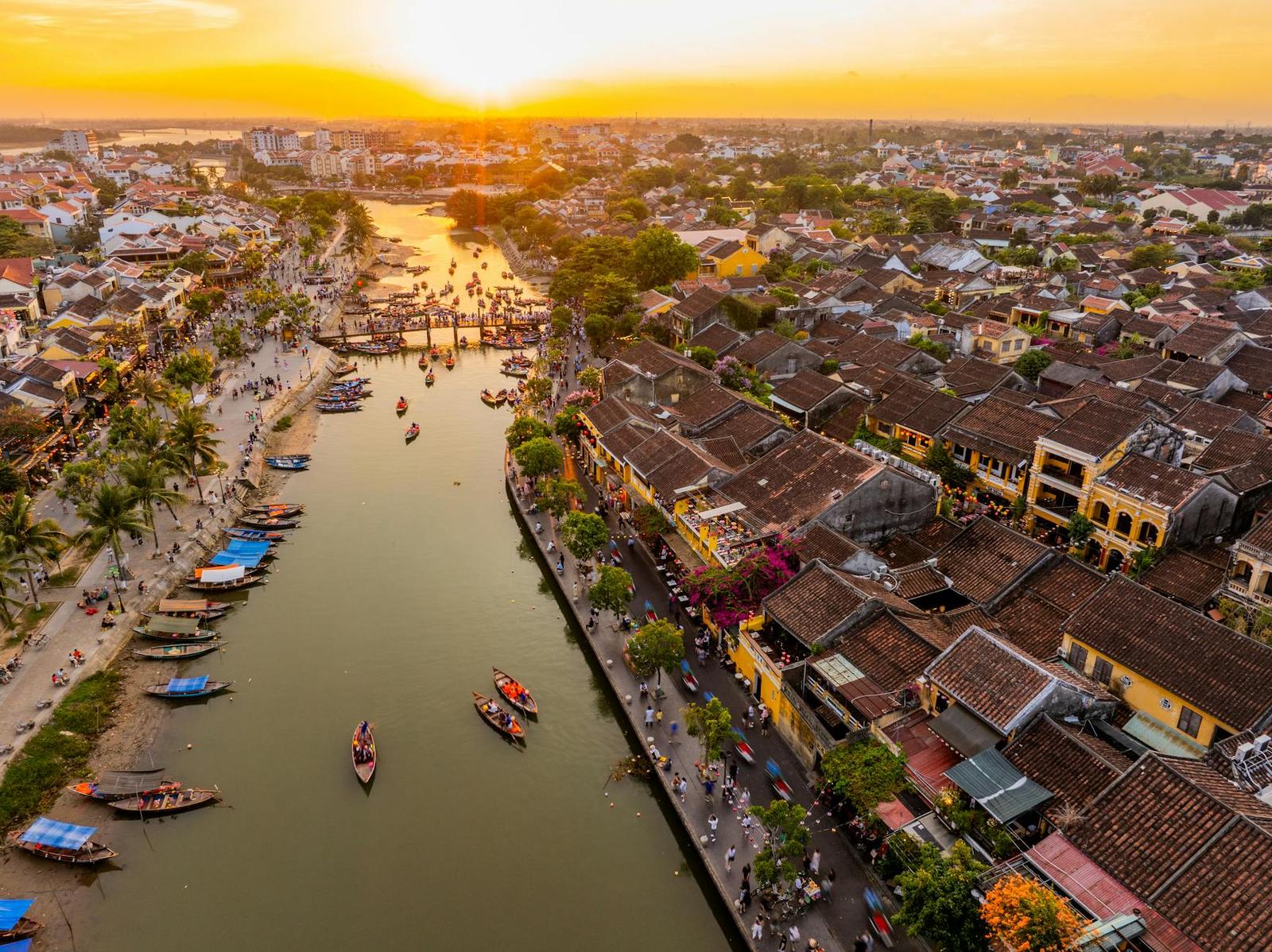 Golden hour aerial view of a riverside old town with tiled roofs and boats
