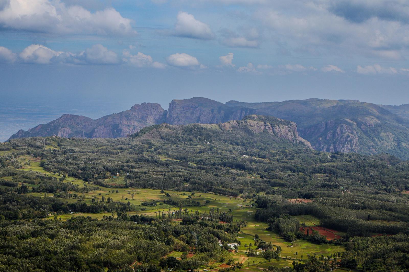 A breathtaking aerial view of lush green valleys and rugged hills under a blue sky in Tamil Nadu, India