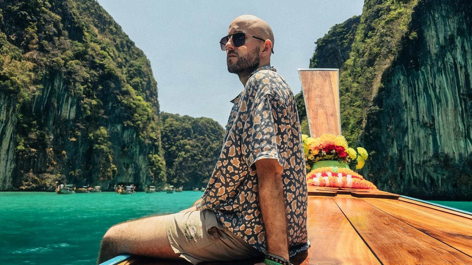 Man enjoying a sunny day on a boat near tropical limestone cliffs