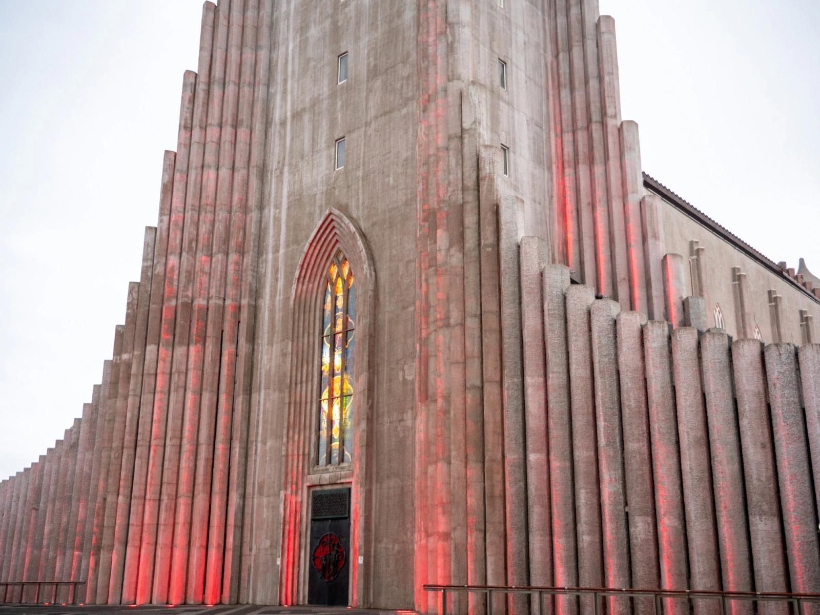A tall church facade with ribbed columns lit in red light