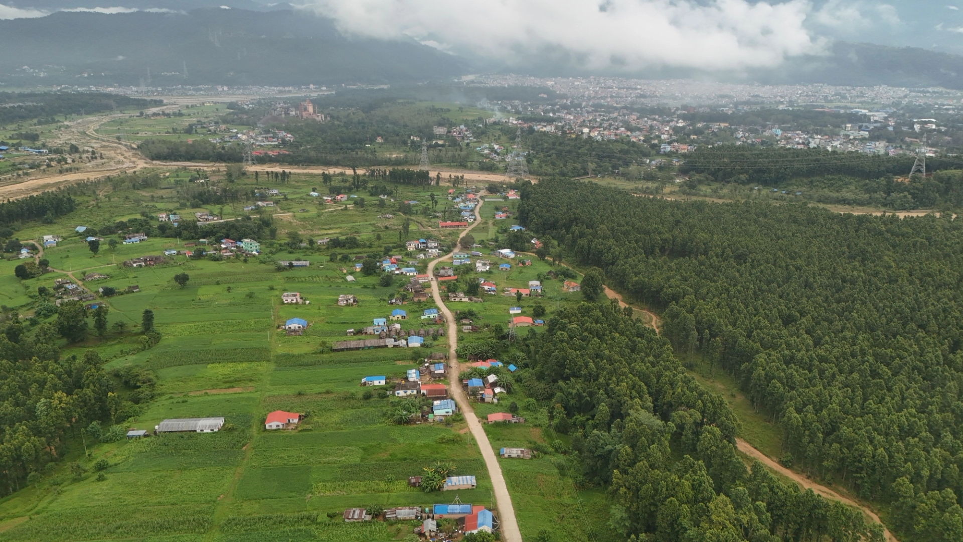 Aerial shot showcasing a sprawling village and lush greenery under clouded skies in Nepal