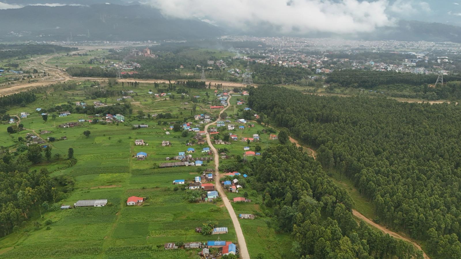 Aerial shot showcasing a sprawling village and lush greenery under clouded skies in Nepal