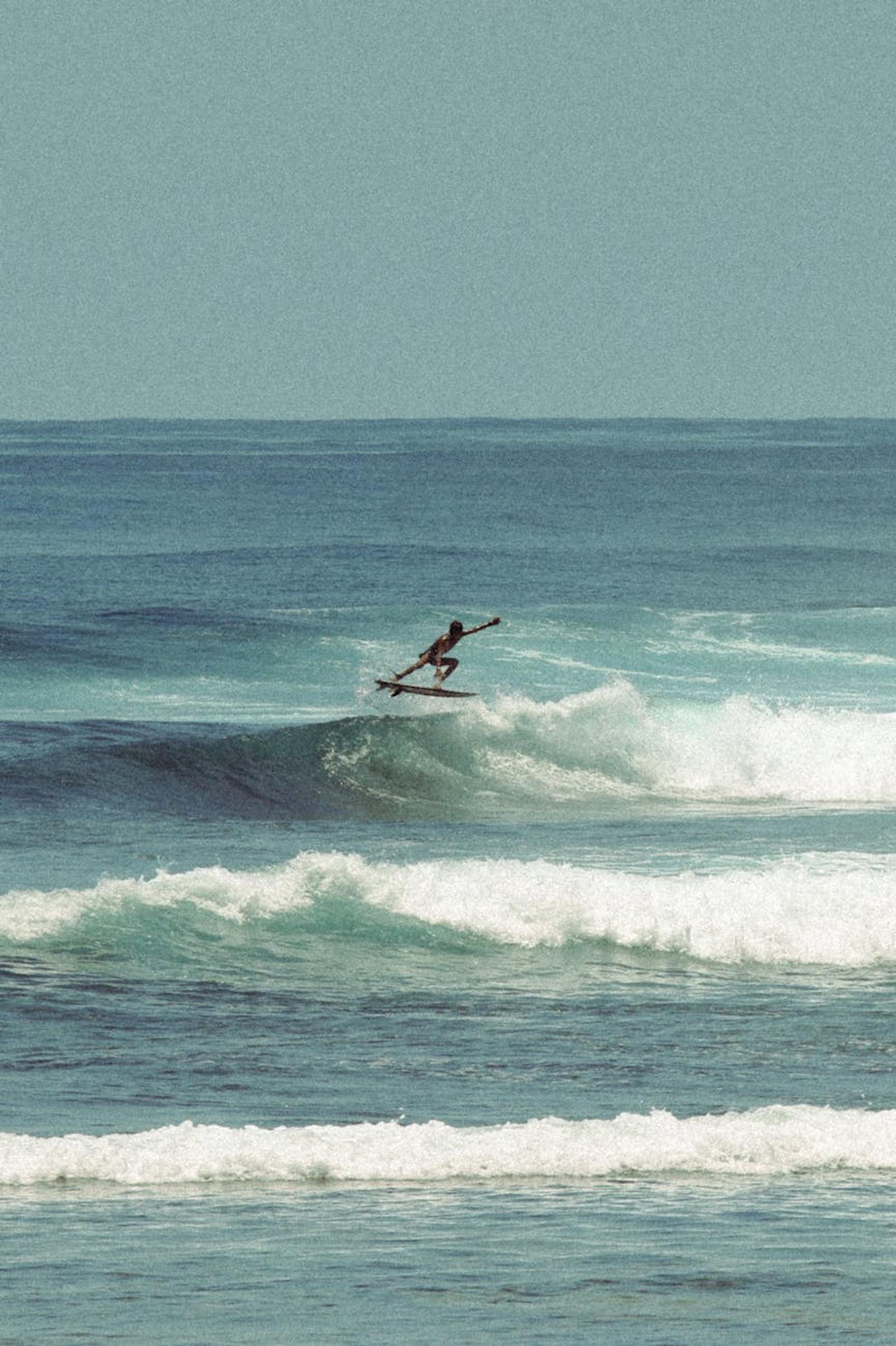 Dynamic scene of a surfer in mid-air over a wave in Bali, Indonesia