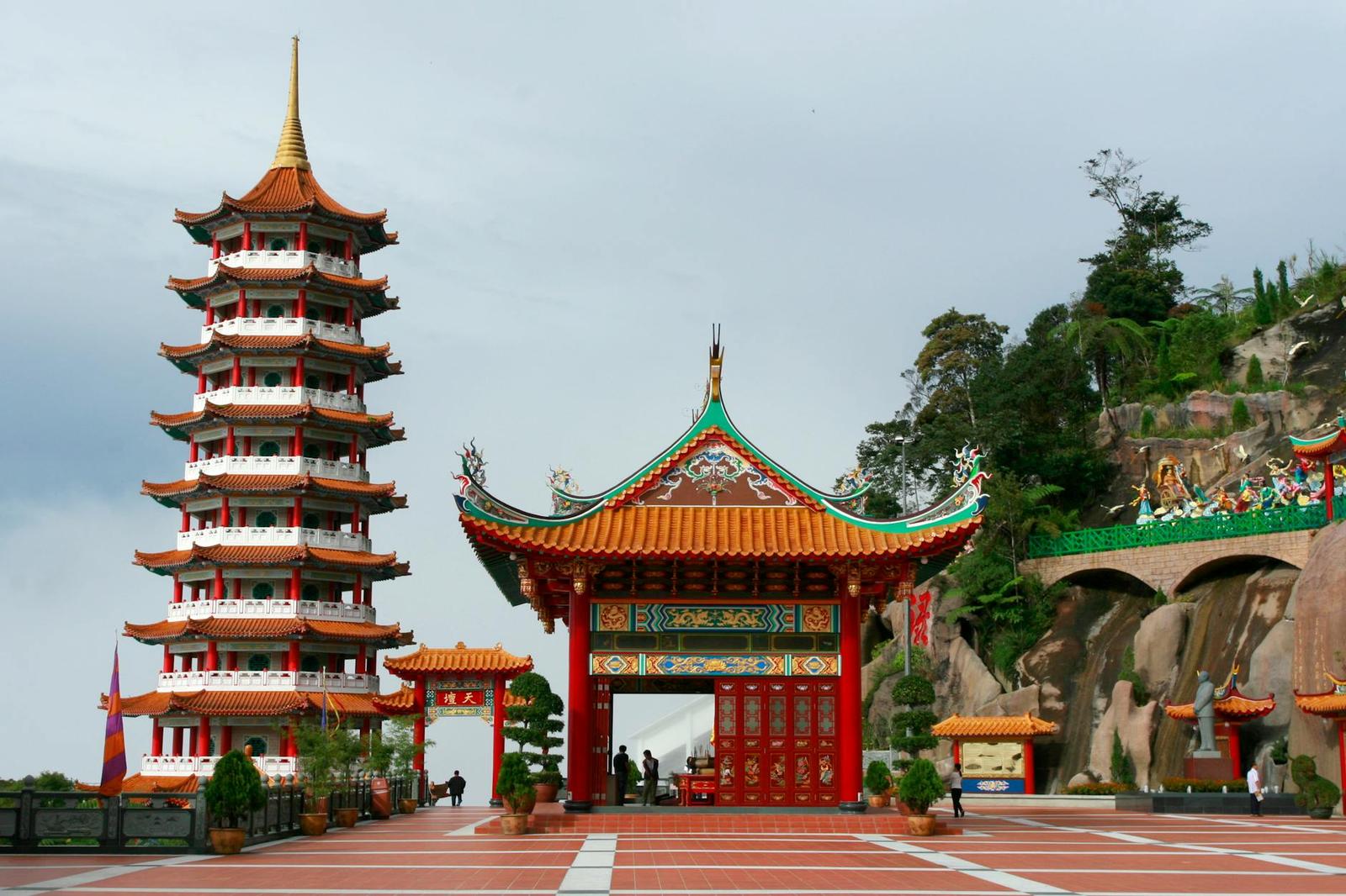 Multi-tiered pagoda beside an ornate red temple gate on a plaza