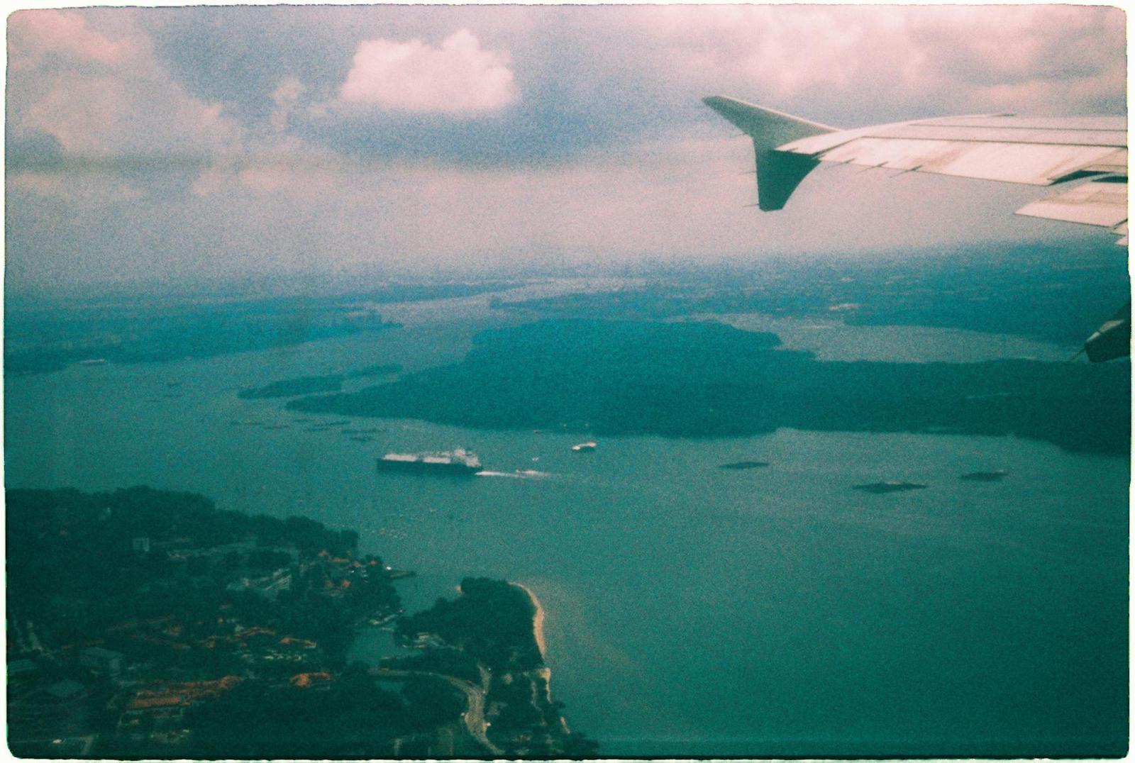 View from an airplane window over islands and ships at sea