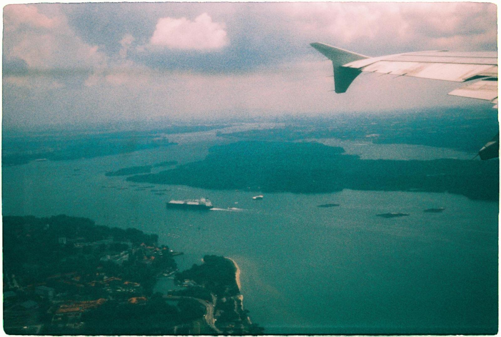 View from an airplane window over islands and ships at sea