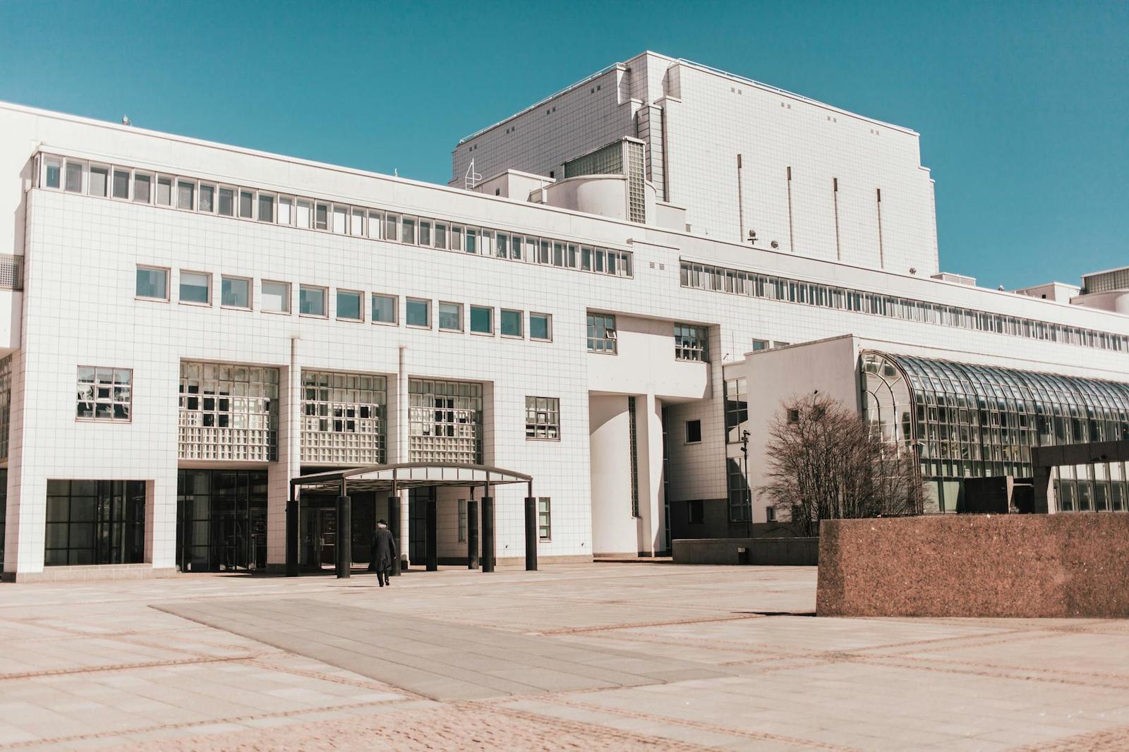 White modernist building facade with a glass entrance canopy
