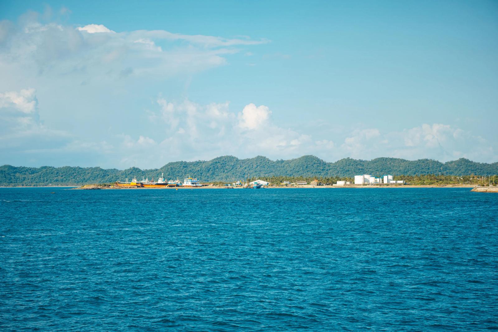 A serene coastal landscape with blue ocean and distant hills under a clear sky