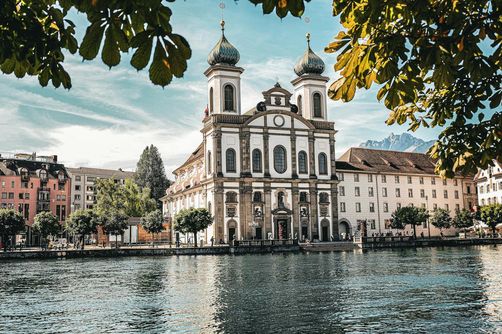 Beautiful capture of the Jesuit Church on Lucerne's waterfront with a picturesque mountain backdrop