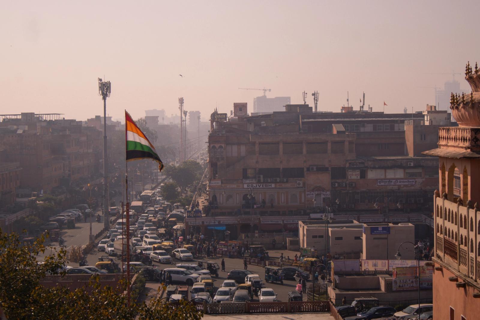 A busy street in Jaipur, India with the national flag waving, conveying a sense of vibrant city life