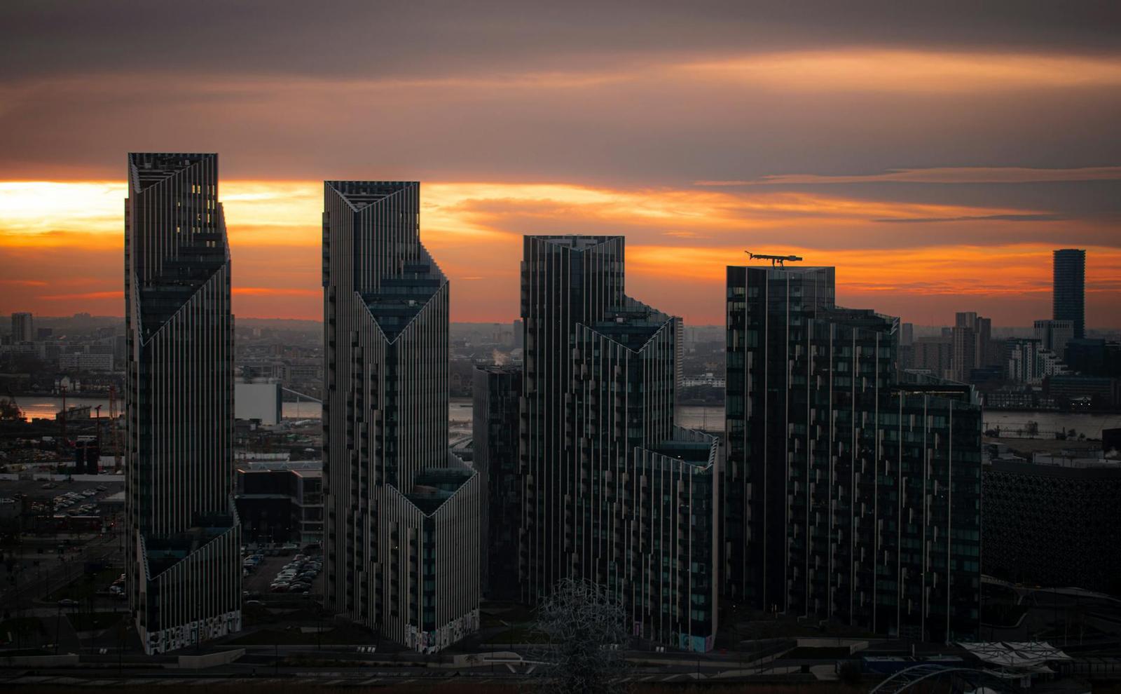 Modern high-rise towers silhouetted against a glowing sunset skyline