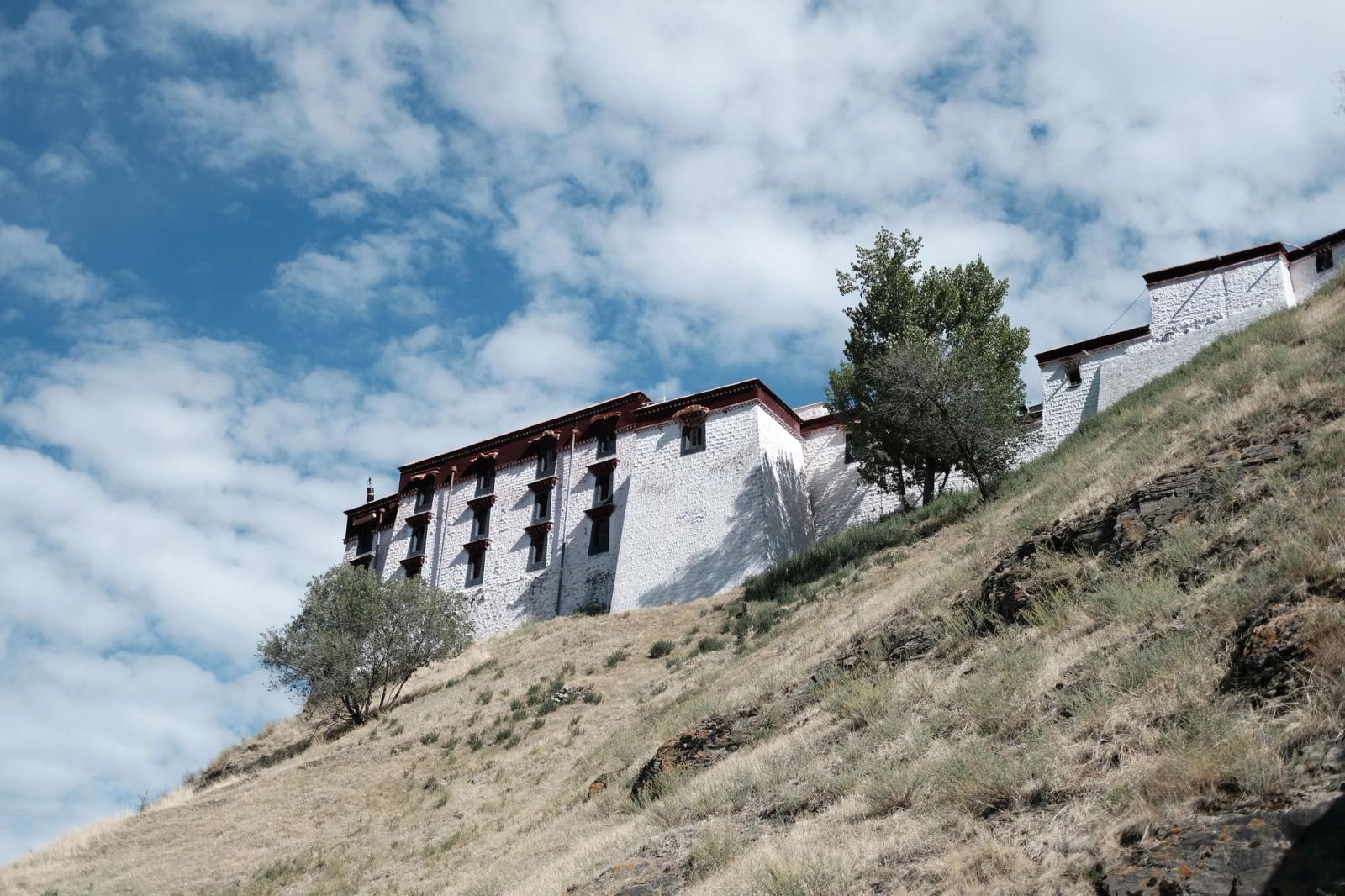 Low angle view of a historic building on a hill with trees and blue sky
