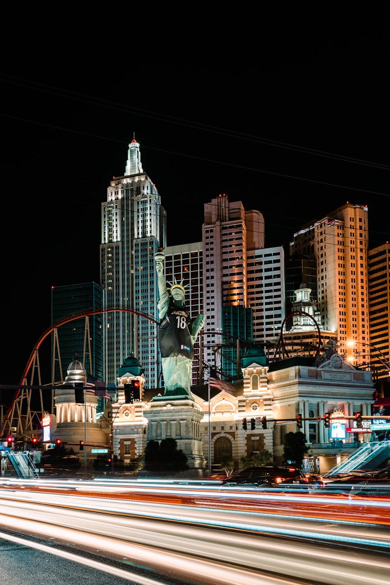 Long exposure night shot of Las Vegas's Statue of Liberty with city lights and modern architecture
