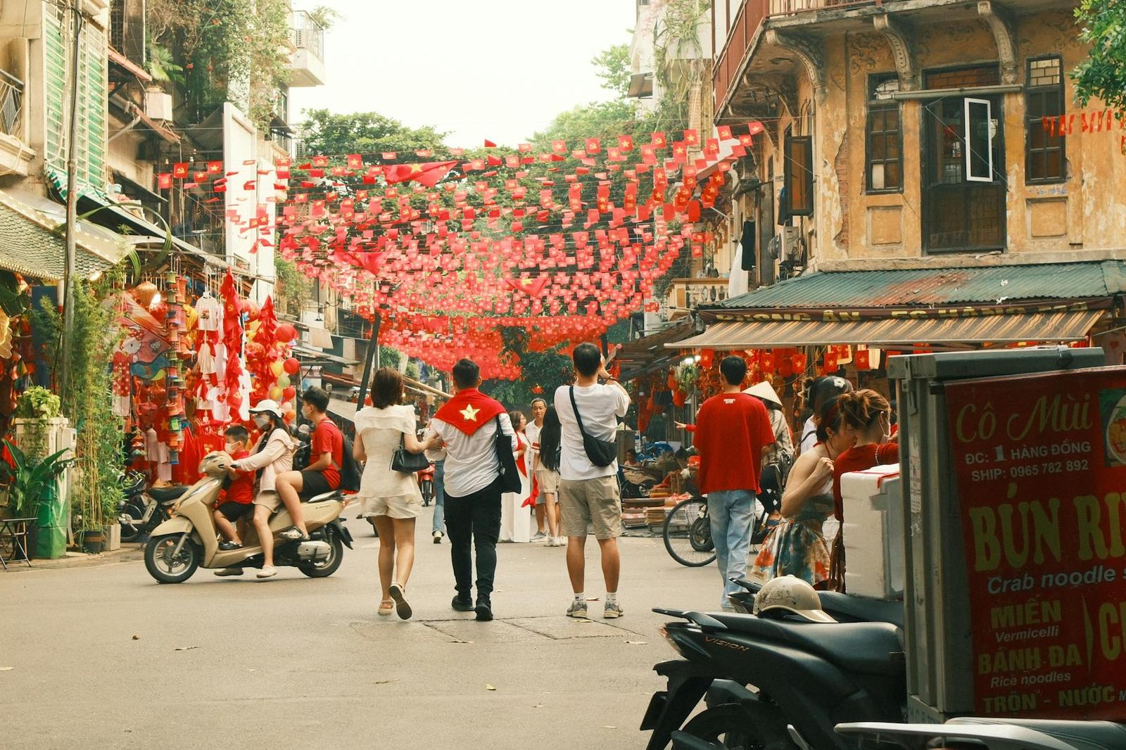 Pedestrians walking an old-town street strung with red festival lanterns