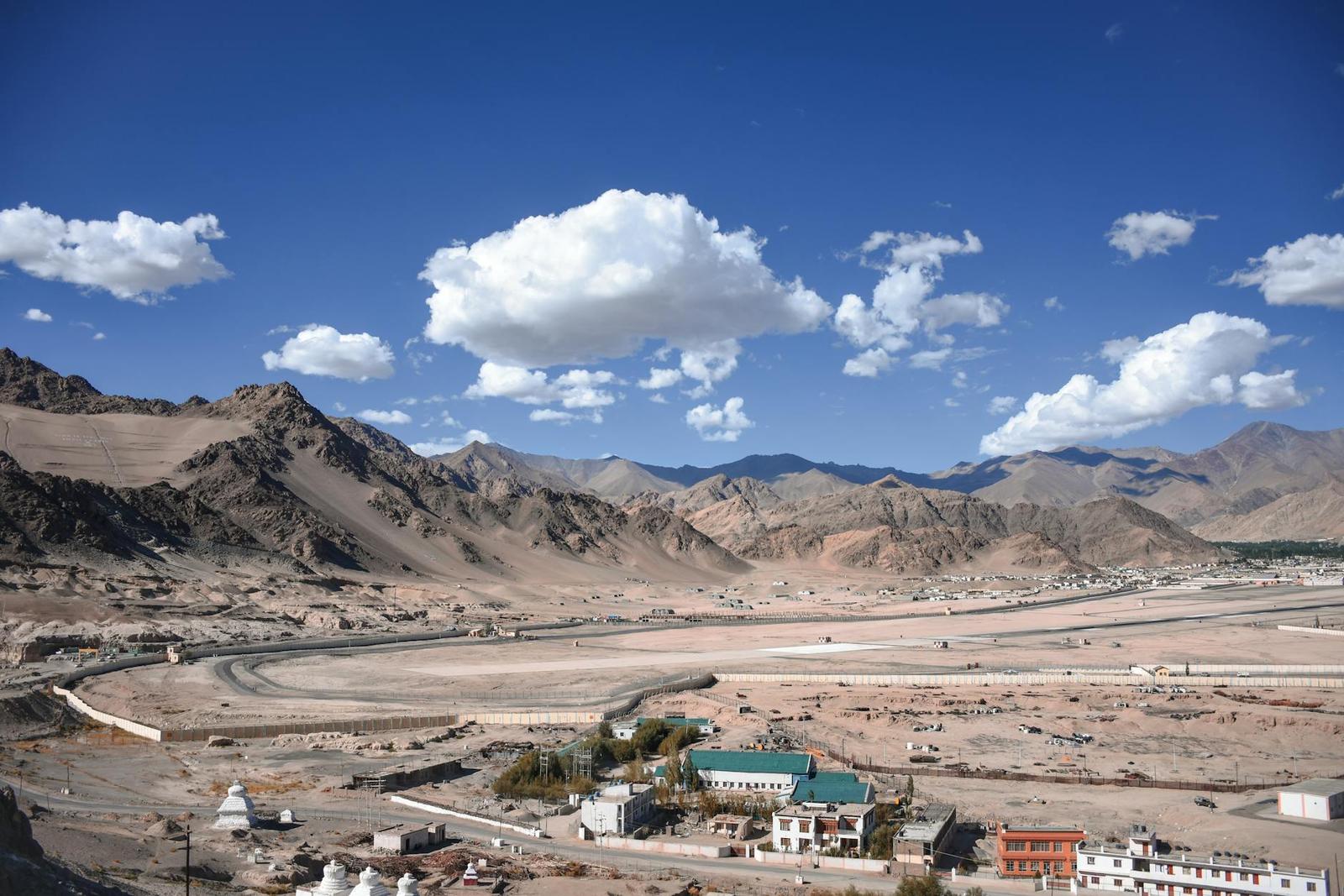 Mountain-ringed valley town with a green-roofed building among desert terrain
