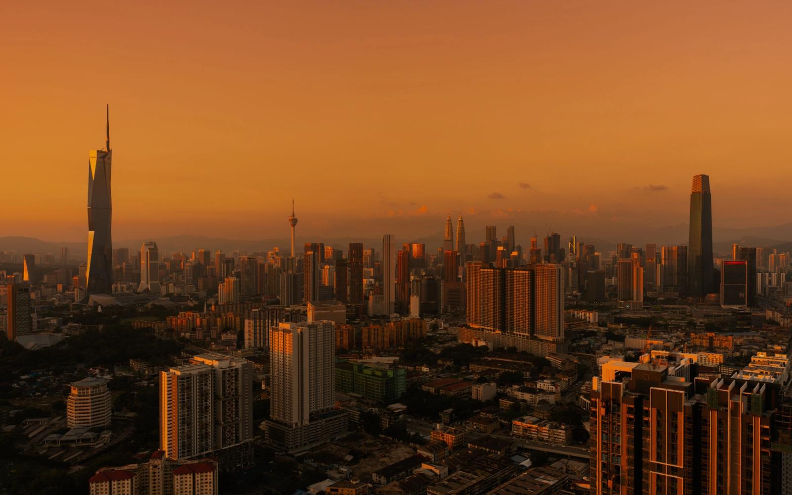 Stunning aerial view of Kuala Lumpur skyline under a warm, golden sunset