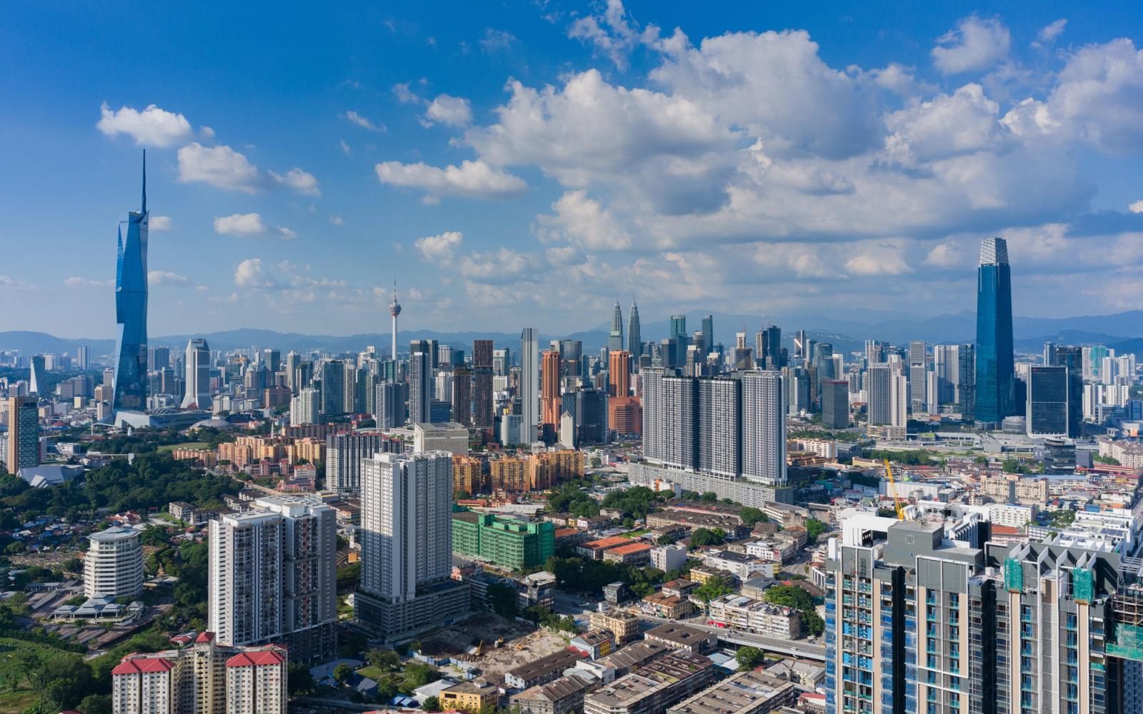 A stunning aerial photograph of Kuala Lumpur's skyline with famous landmarks under a vibrant blue sky