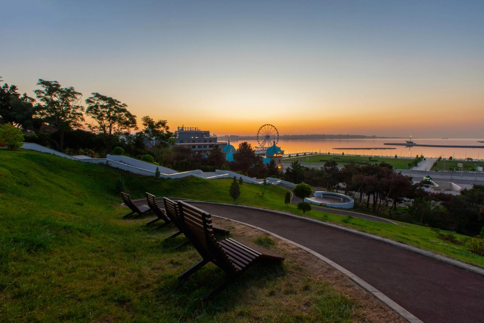 Capture the serene sunset in Baku, Azerbaijan, featuring a stunning Ferris wheel along the coast