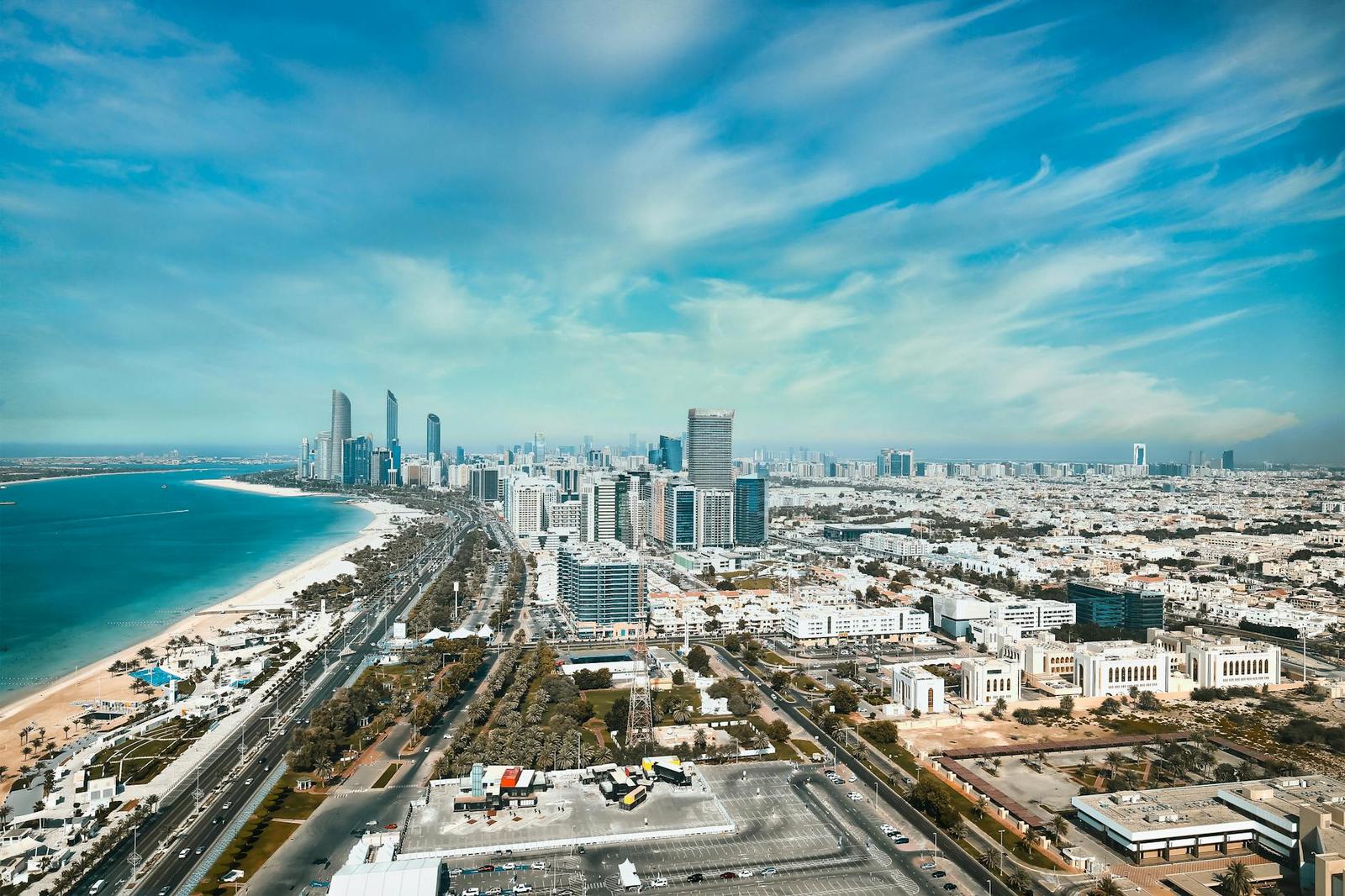 Aerial view of a coastal city skyline beside a sandy beach and highway