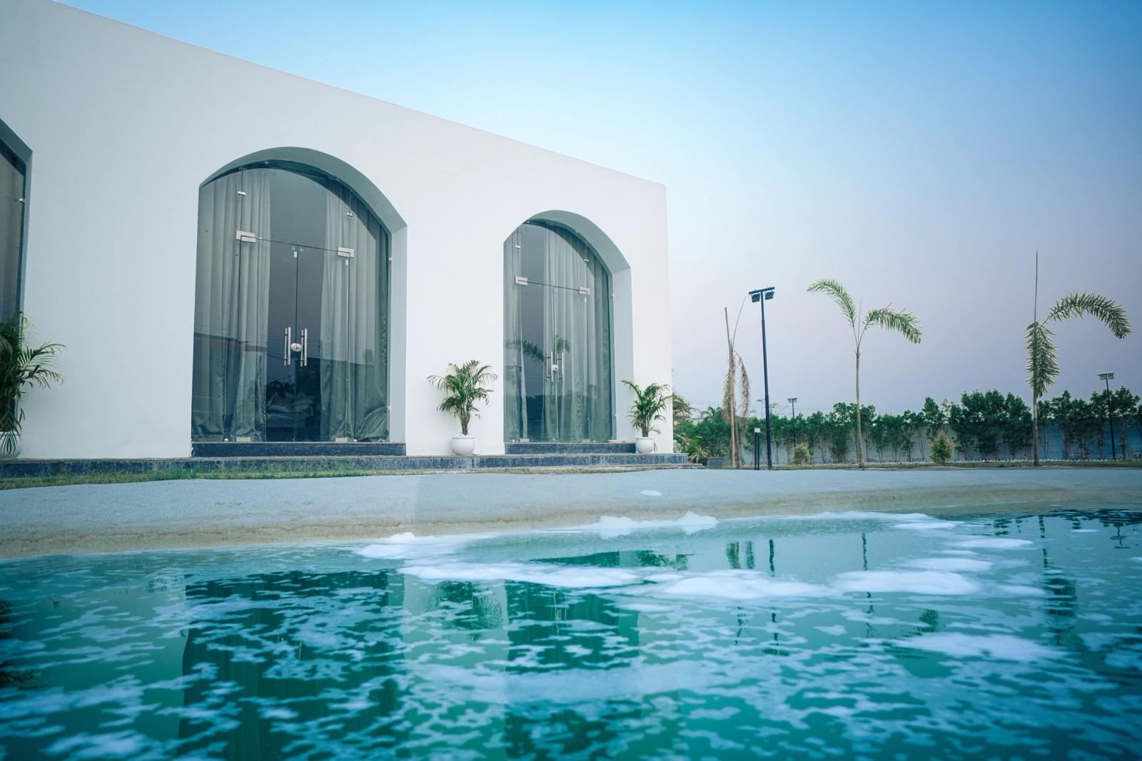 Contemporary villa with arched glass doors and a luxurious swimming pool surrounded by palm trees
