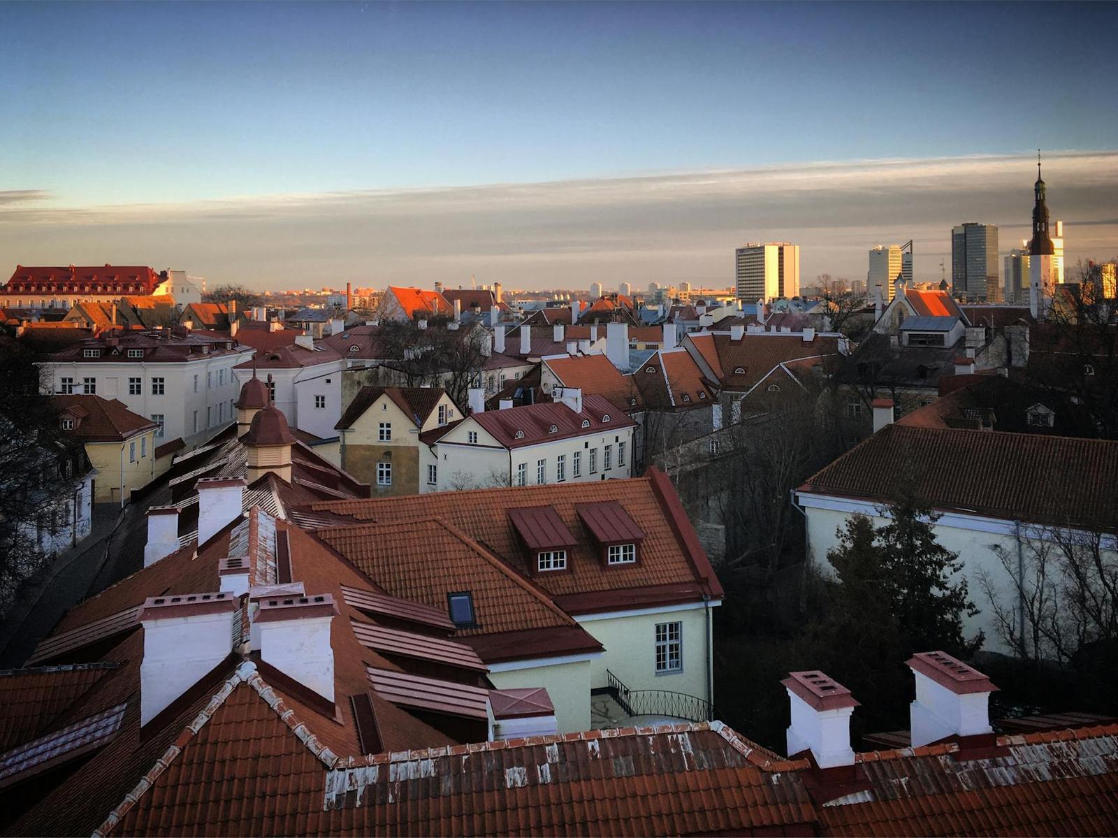 An elevated view of red-tiled rooftops and church spires stretching to a hazy skyline