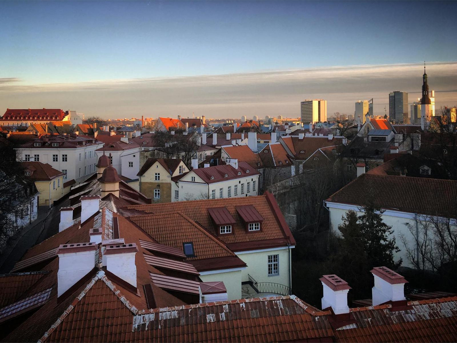 An elevated view of red-tiled rooftops and church spires stretching to a hazy skyline