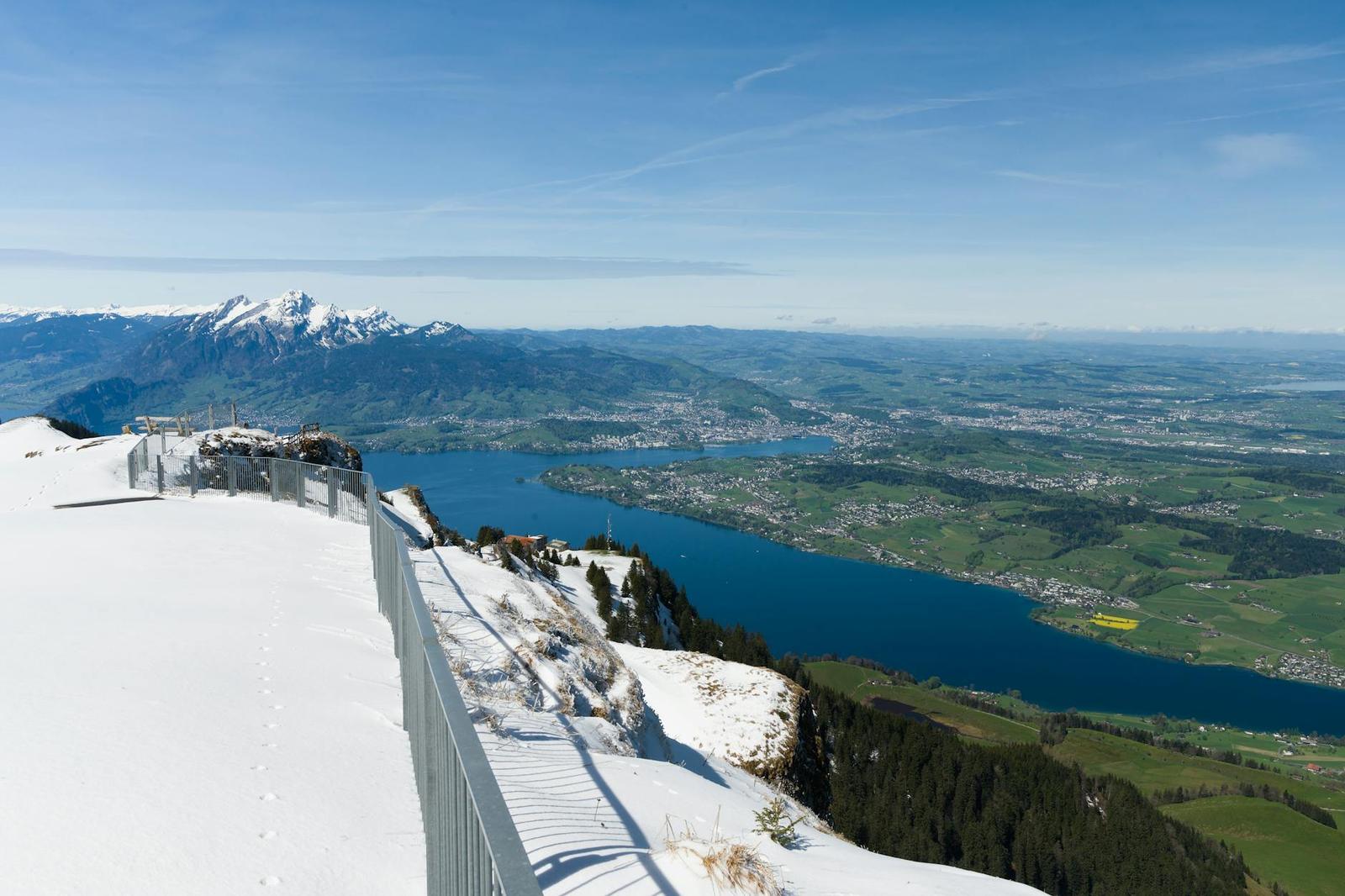 Snow-covered mountain viewpoint overlooking a blue lake and valley
