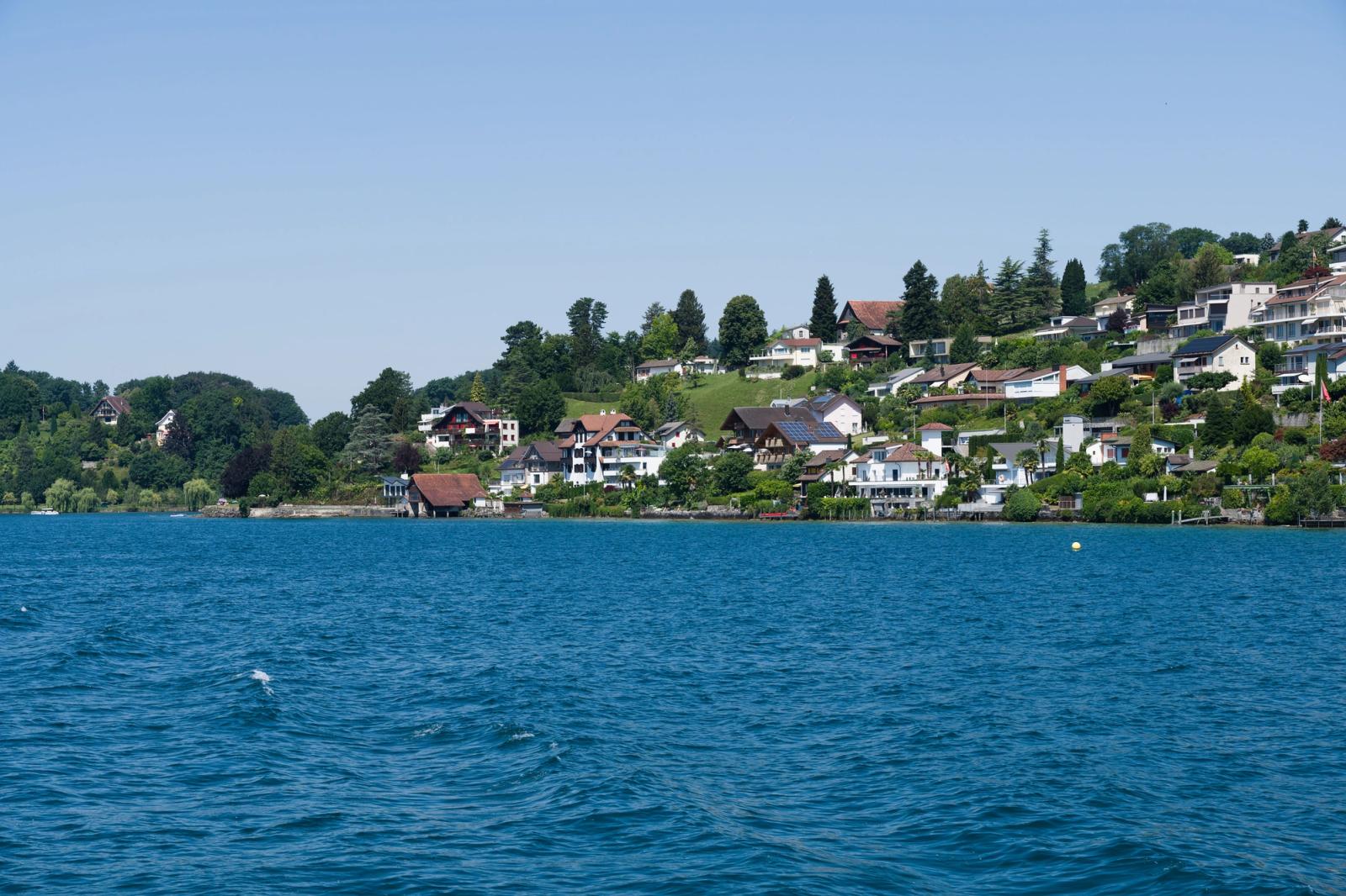 Picturesque landscape of lakefront homes in the Swiss countryside, capturing serene beauty and lush greenery