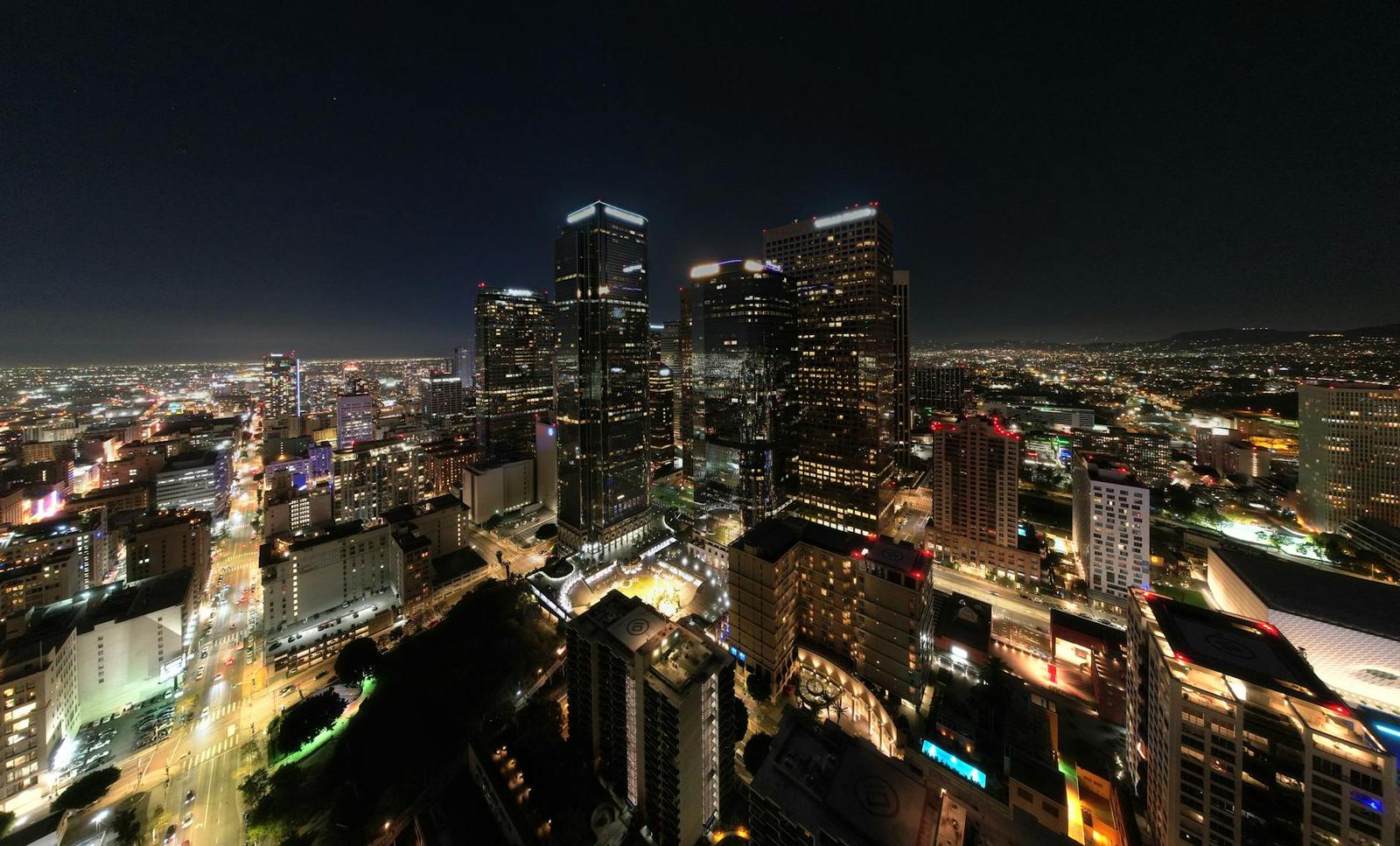 An aerial night view of downtown high-rises above streaks of city traffic
