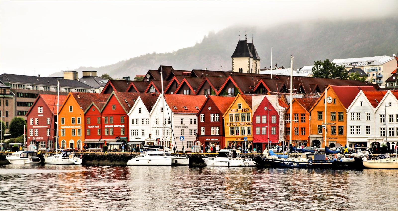 Row of colorful gabled wooden buildings along a harbor with boats