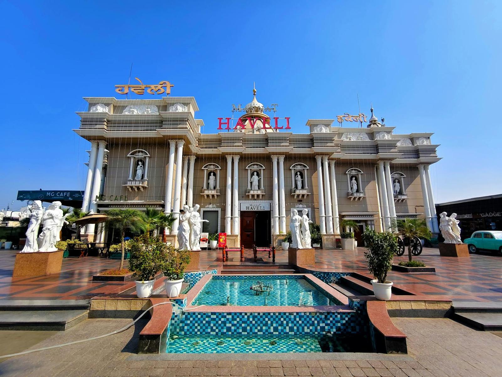 An ornate pillared building with statues around a tiled fountain courtyard