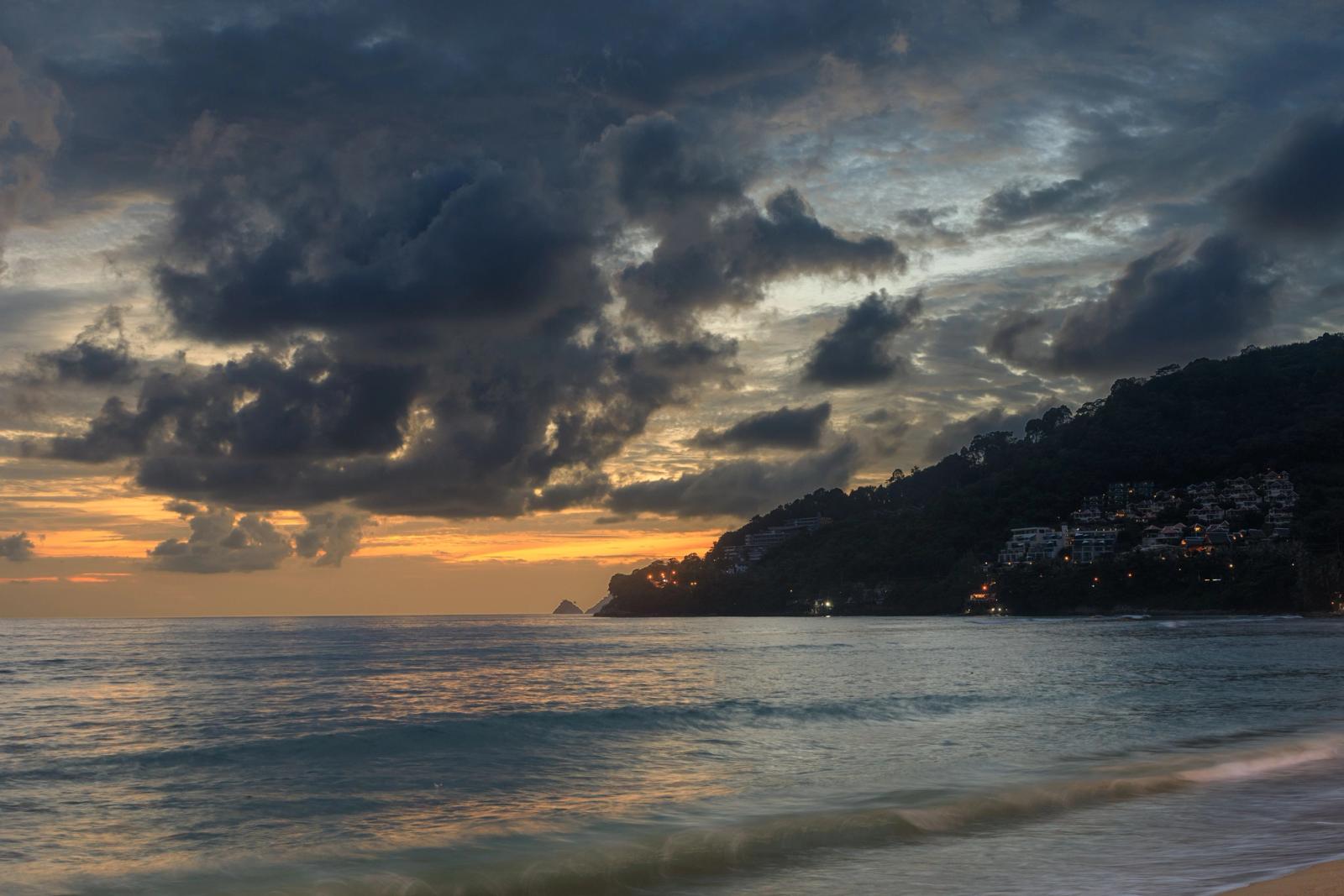 Stunning sunset over Patong Beach, Phuket, with dramatic clouds and calm waves