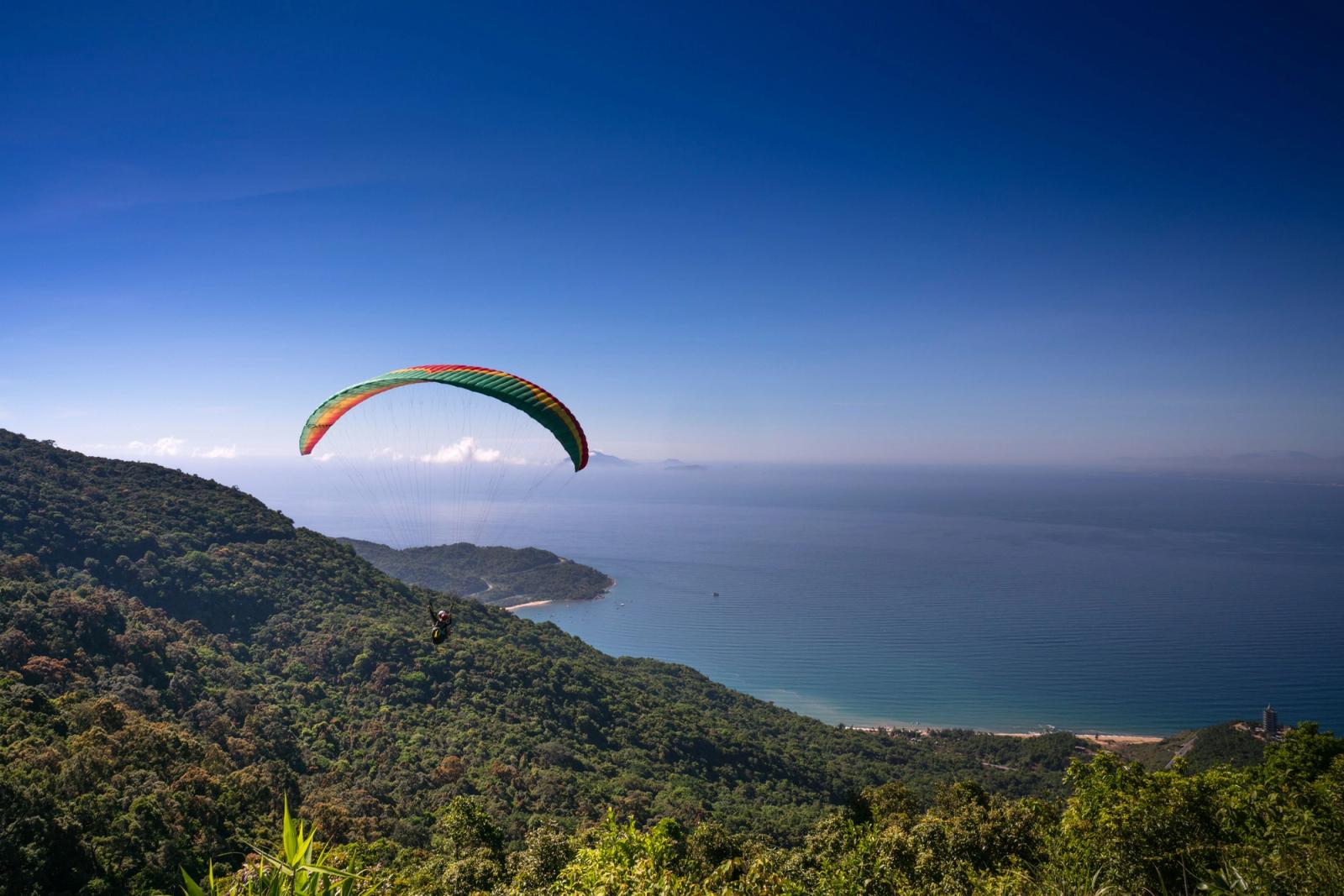 A paraglider soars above the lush Sơn Trà Peninsula with stunning ocean views in Đà Nẵng, Vietnam