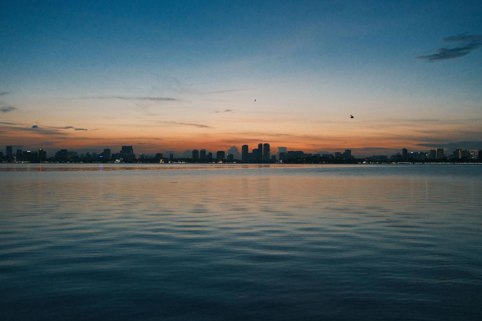 Peaceful sunset scene over West Lake with city skyline in Hanoi, Vietnam