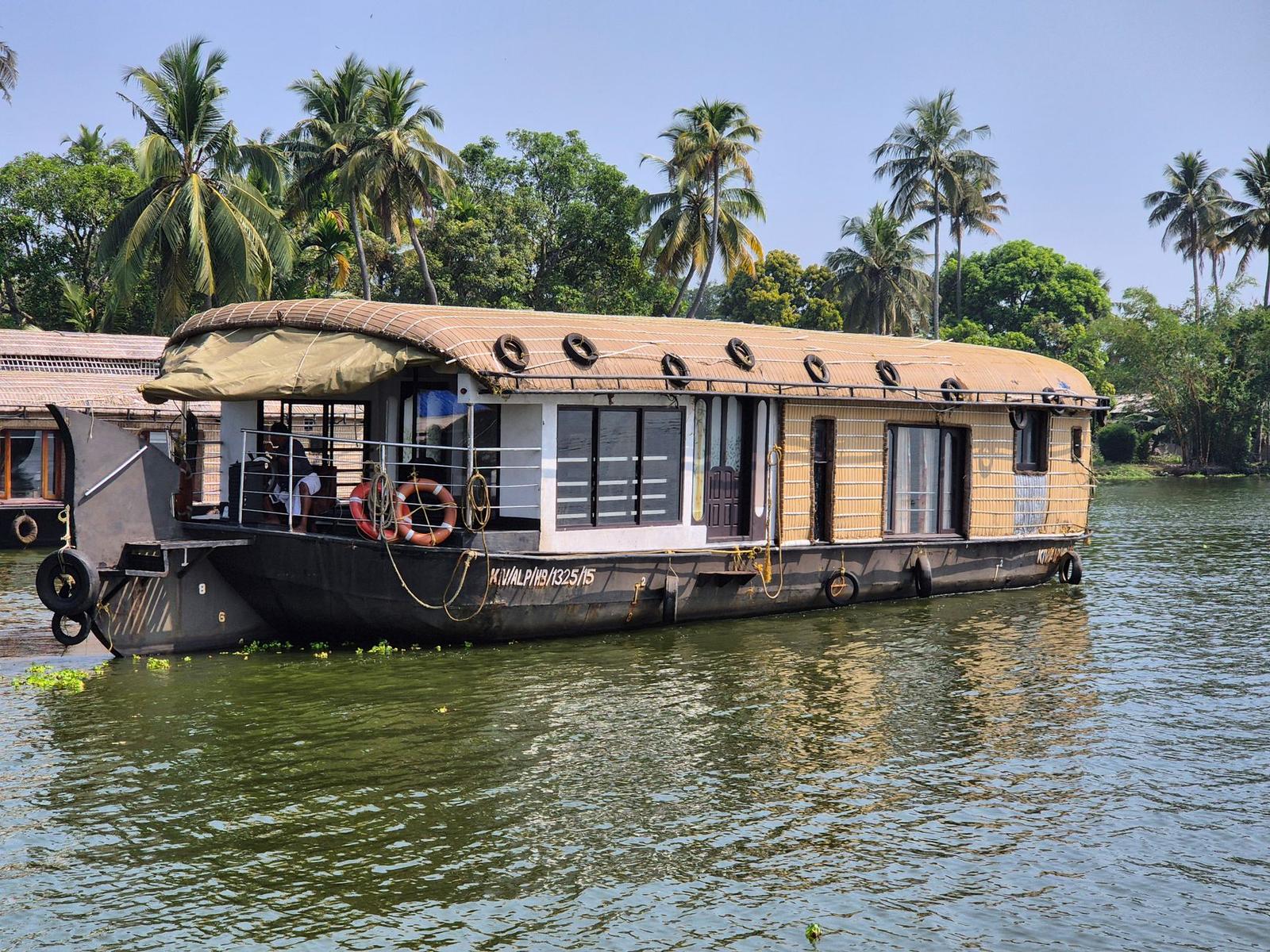 Charming houseboat floating on Kerala backwaters surrounded by tropical palm trees