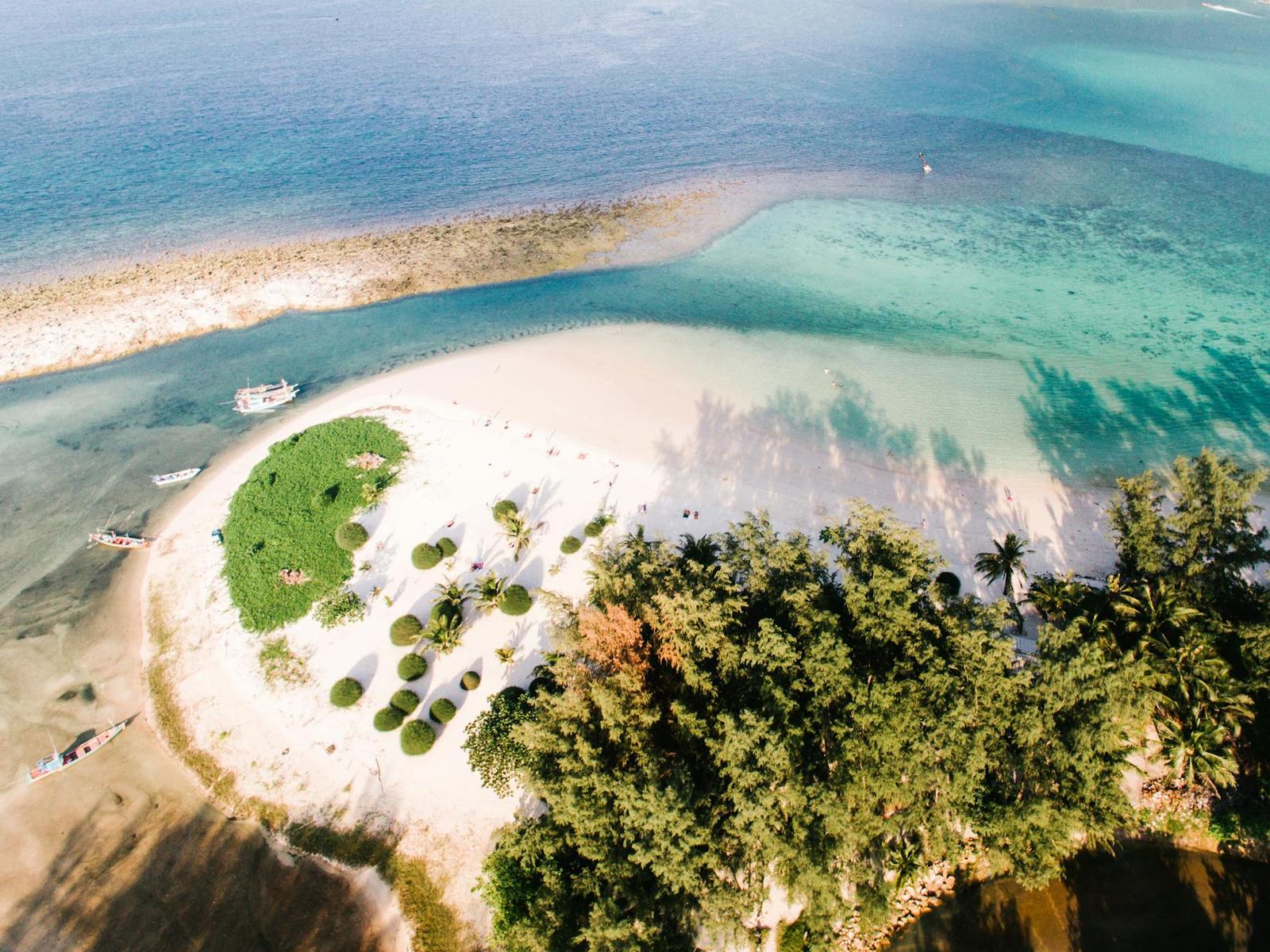 Aerial view of a sandy islet with a green mound between two shades of water