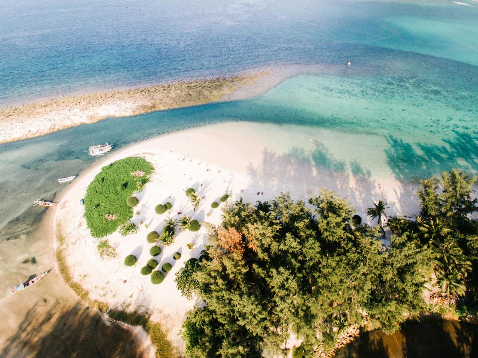 Aerial view of a sandy islet with a green mound between two shades of water